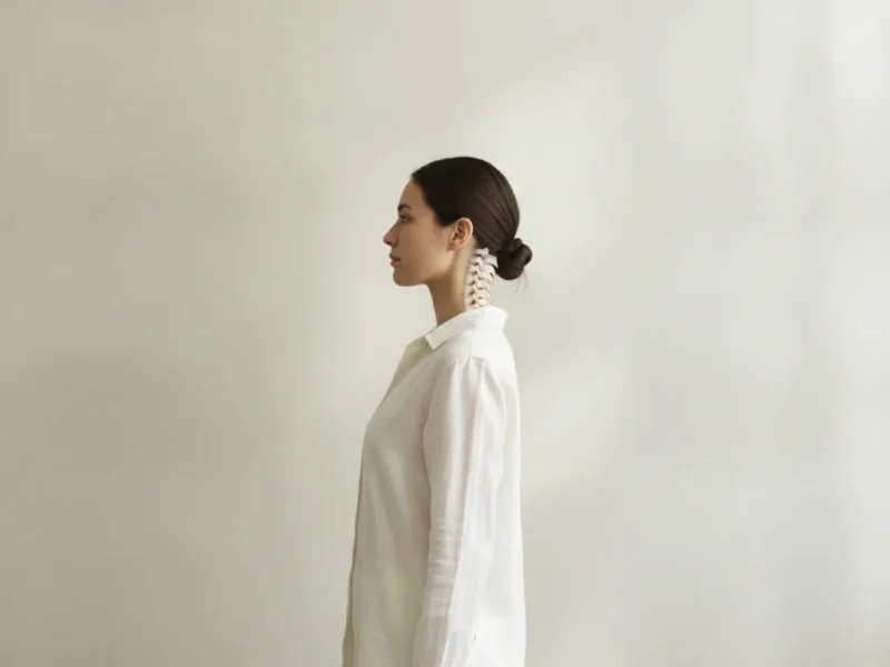 Femme debout adoptant une bonne posture, dos droit et épaules détendues dans un intérieur lumineux.
